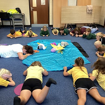 children and author laying flat on the floor around the blue blanket