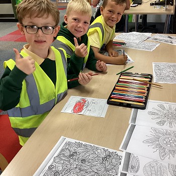 children wearing hi-viz jackets and colouring pictures