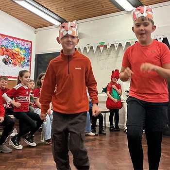 Two children wearing red dancing in the assembly