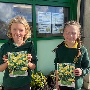 Two children holding a packet of daffodul bulbs seeds