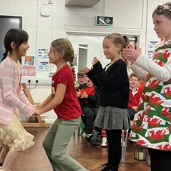 Two children dancing with other children clapping