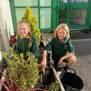 Two children enjoying their time planting daffodil bulbs