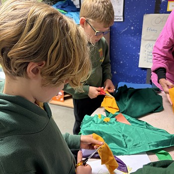 children cutting coloured fabrics with scissors