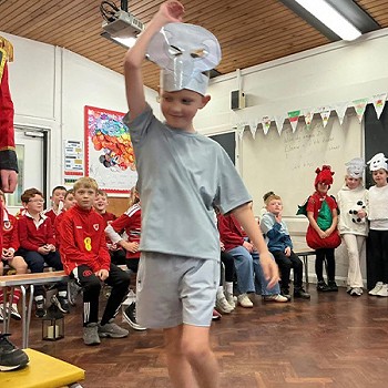 A child wearing grey dancing in the assembly