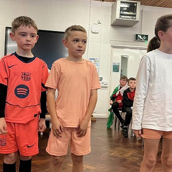 Three children taking part in an acting scene in the assembly