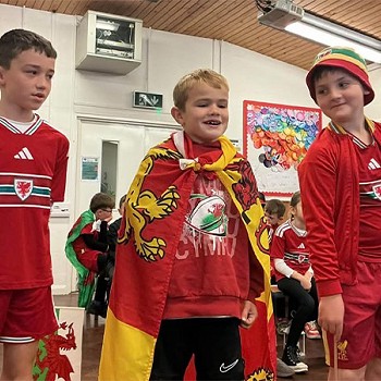 Three children wearing red and taking part in the assembly